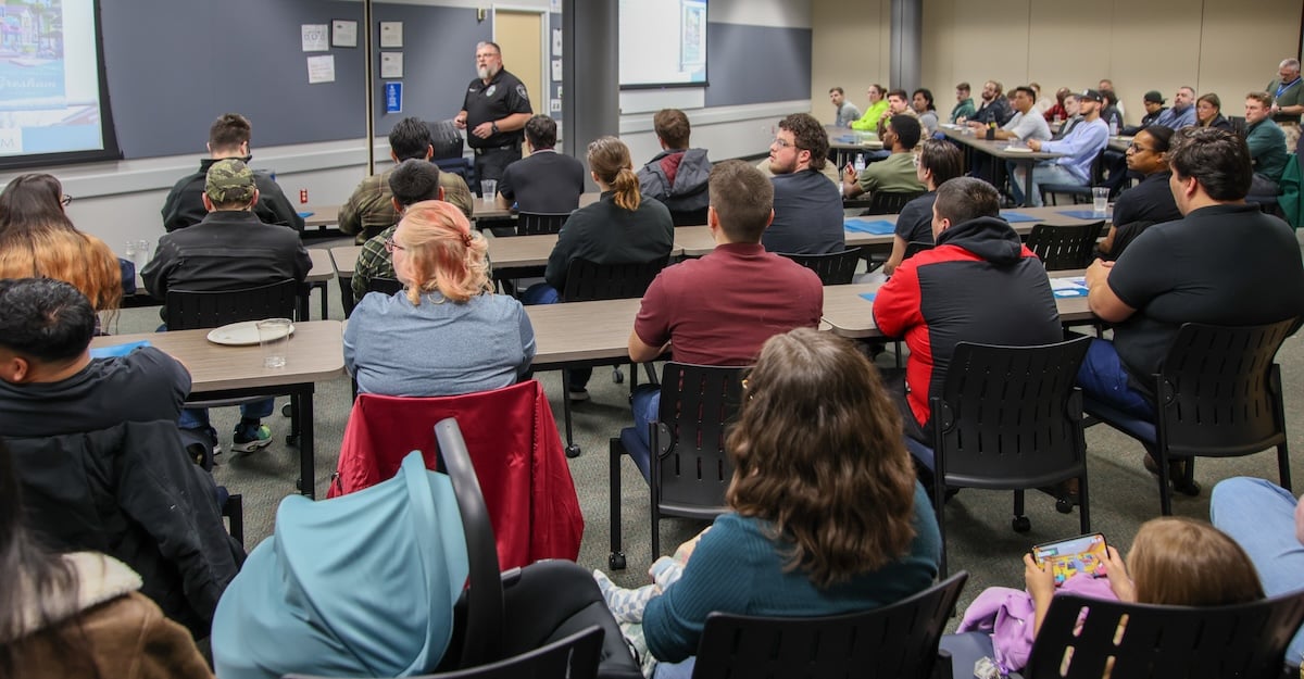 People sitting to listen to an officer speak at a Gresham Police open house.
