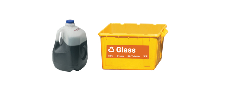 Motor oil in plastic jug set by a glass recycling bin.