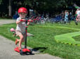 Child riding on scooter in a park.